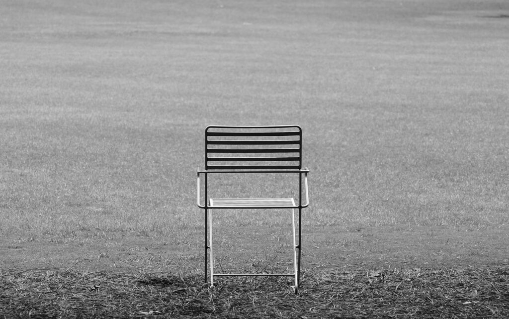 Single metal chair sitting alone in a vast, empty grey landscape
