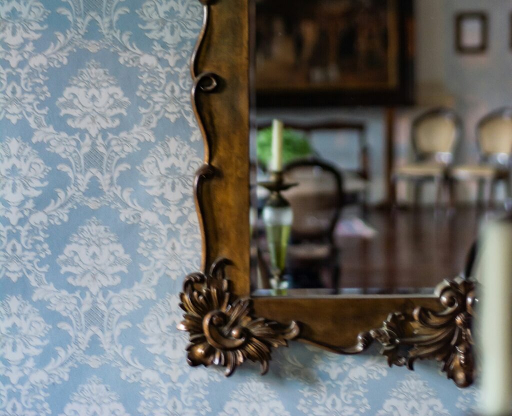 Ornate antique mirror frame reflecting a blurred interior room